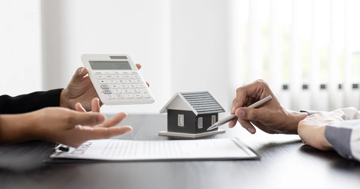 Hands discussing house finances with calculator and model home